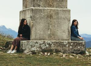 Women sitting opposite sides of a Piller