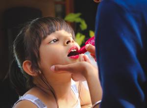 Self-conscious girl Having a Lipstick Applied on Her Lips